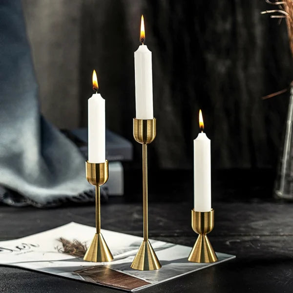 Set of three gold aluminum candle holders with varying heights and minimalist design