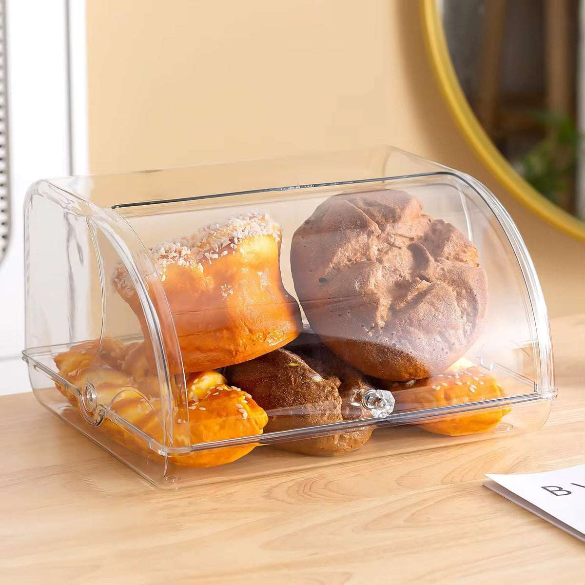 Clear acrylic bread bin with lid used for storing bread, pastries, and baked goods.