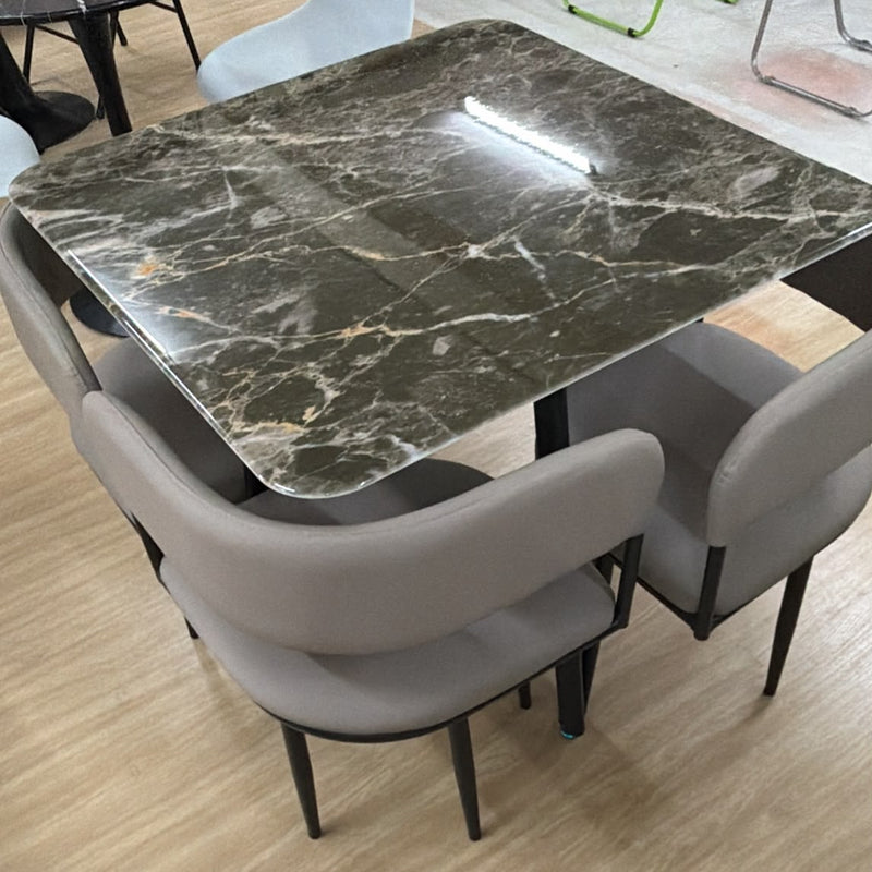 rectangular dark green marble dining table with gold veining and four gray upholstered dining chairs with black metal legs.