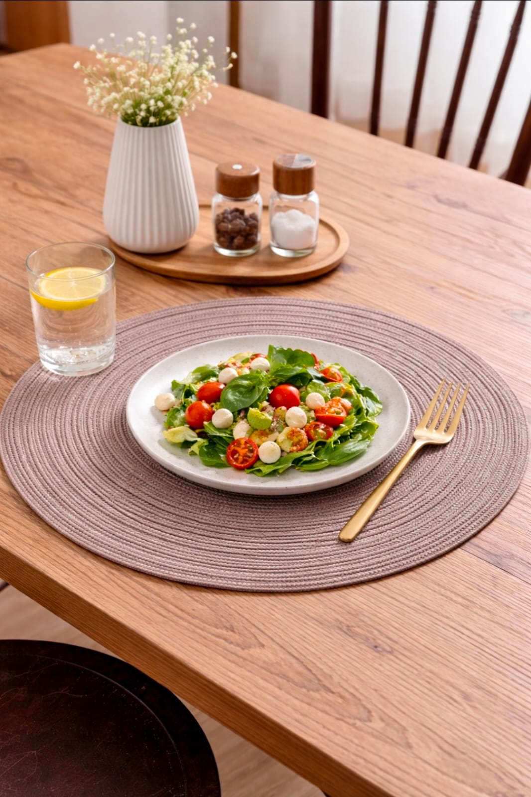 Set of 6 round woven placemats in grey and brown, durable and washable, displayed on a dining table.