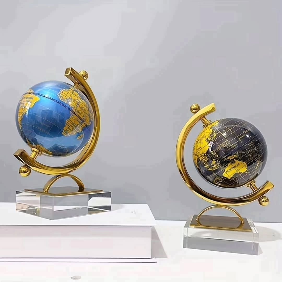 Gemelli Collections rotating world globe decor with gold meridian frame and clear crystal base, available in ocean blue and midnight black finishes.