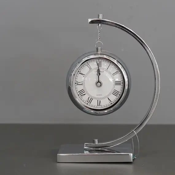 Gemelli Collections silver hanging tabletop quartz clock with polished chrome arch stand, Roman numeral dial, and modern executive desk design.