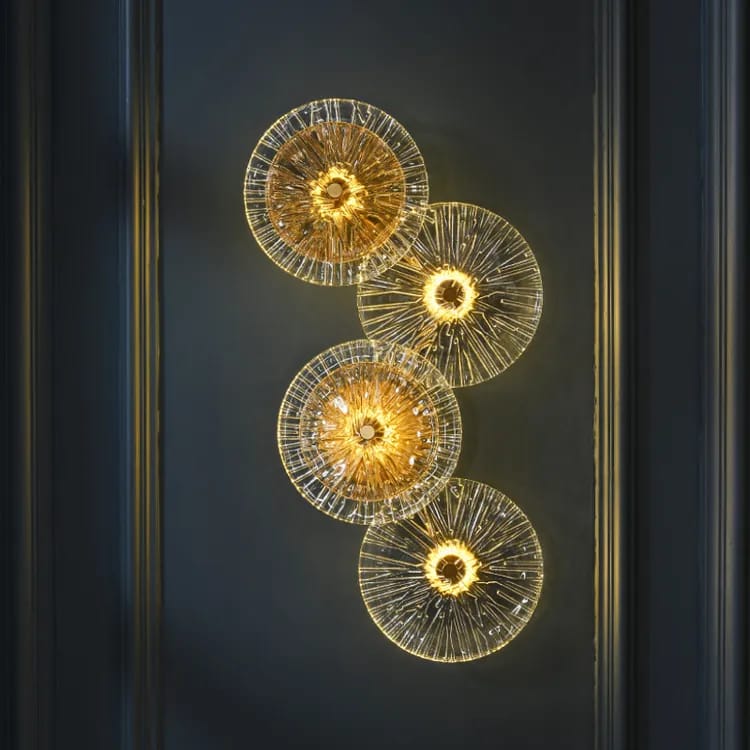 Vertical wall sconce with four layered crystal discs in clear and amber glass mounted on a gold backplate