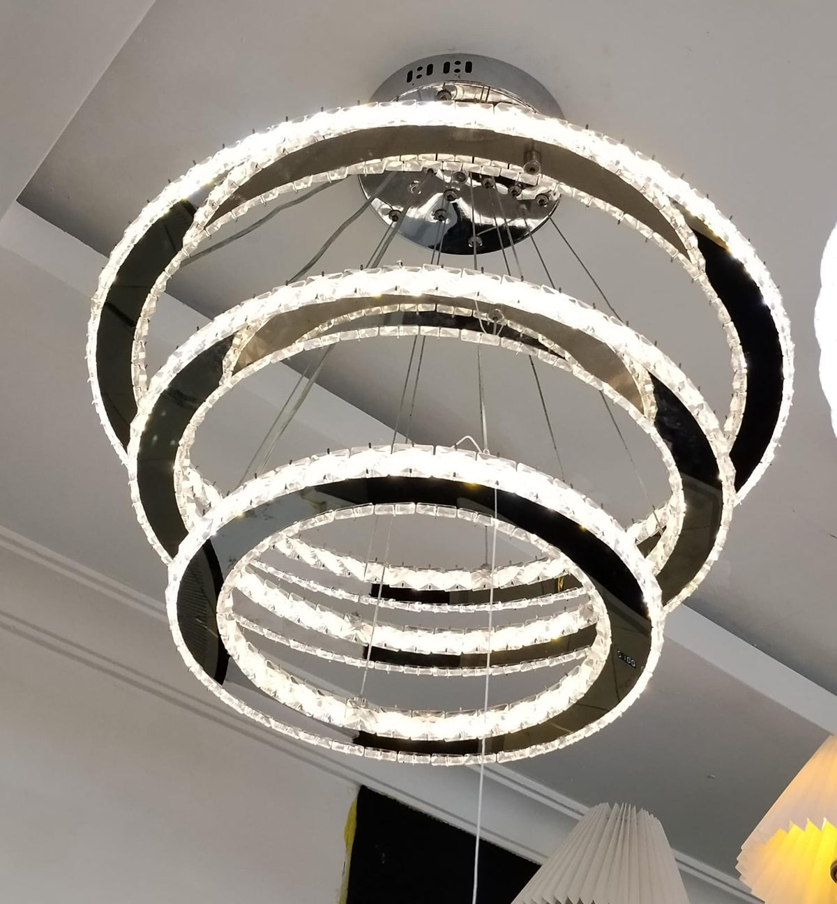 4-ring spiral crystal chandelier with chrome finish, interlocking halo rings, and integrated LED lighting.