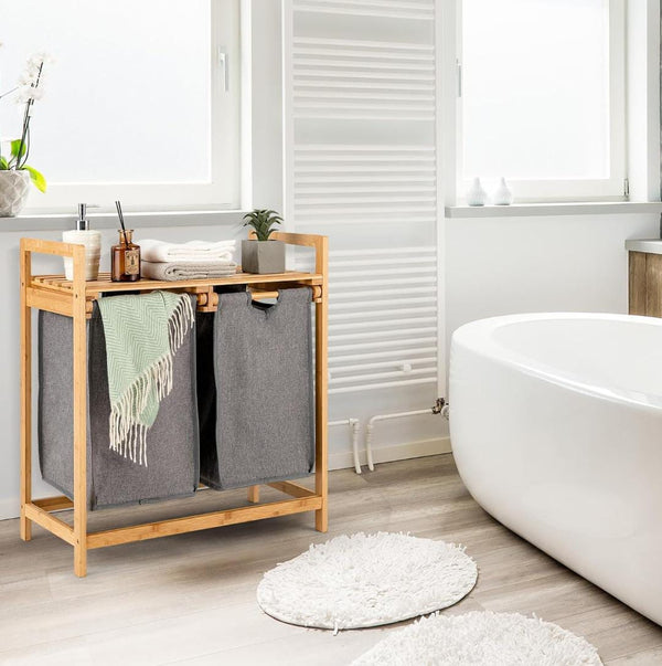 Bamboo twin partition laundry organizer with pullout bags and storage shelf in bathroom