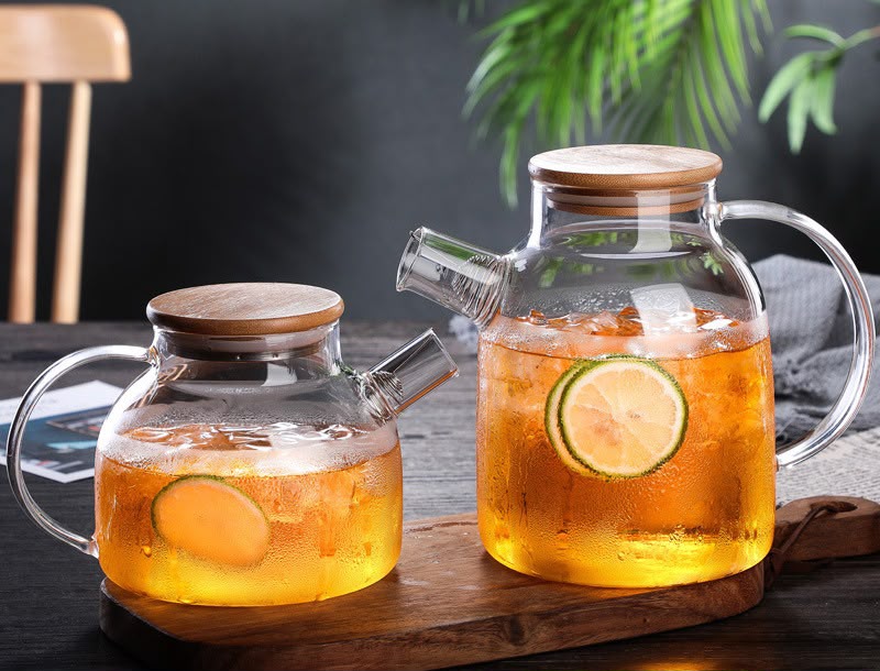 Borosilicate glass cold water pitcher with bamboo lid ergonomic handle and pouring spout available in 1.5 litre and 1.8 litre capacities for water juice and iced tea